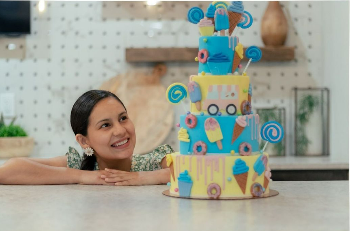 Deisy smiles beside one of her colorful cakes